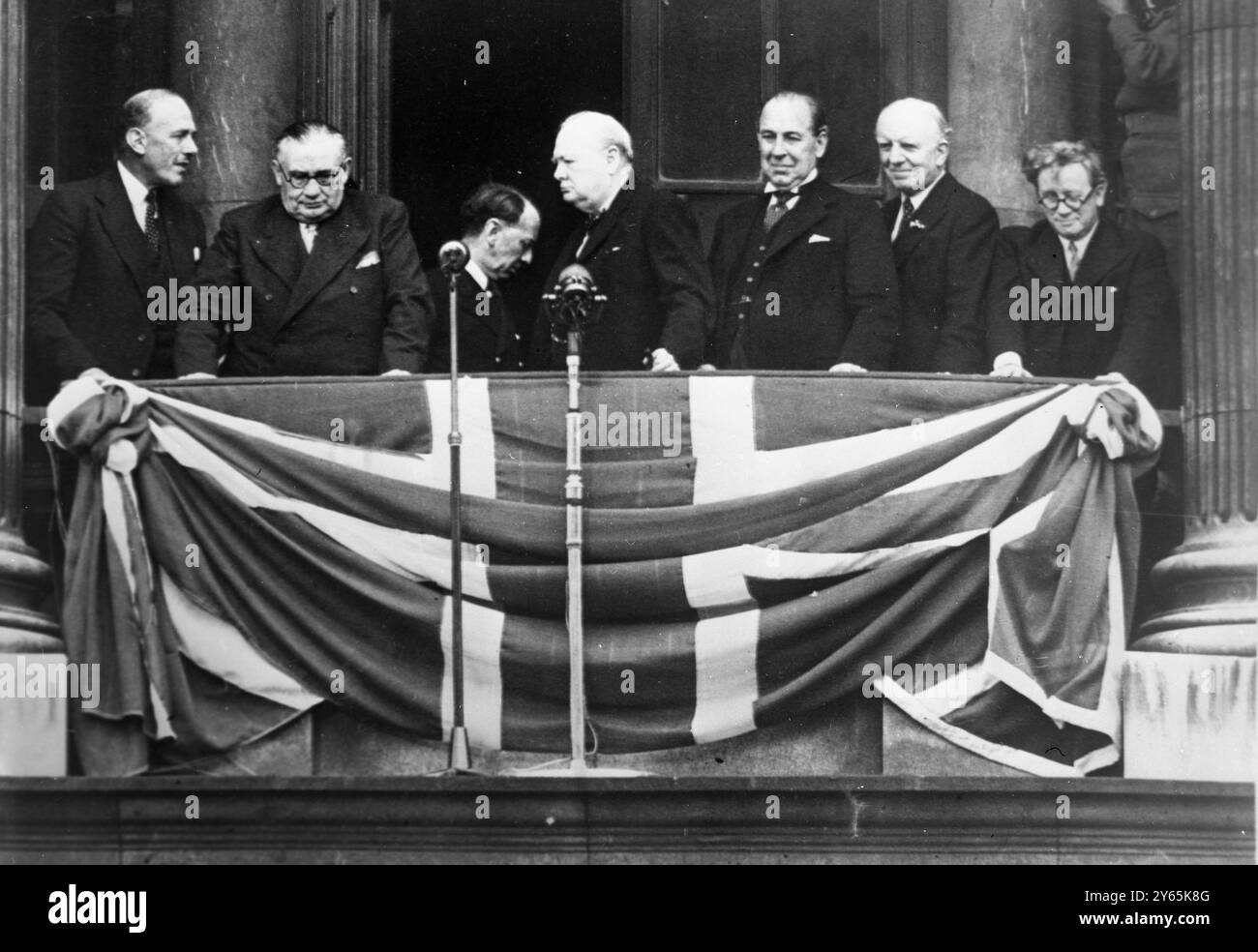 VE Day Crowd Acclaims Churchill . Winston Churchill ( au centre ), premier ministre de la guerre, avec des collègues du Cabinet de guerre sur le balcon du ministère de la santé , Whitehall , Londres . De gauche à droite ; Oliver Lyttleton , Ernest Bevan , Winston Churchill , John Anderson , Lord Woolton et Herbert Morrison . 8 mai 1945 Banque D'Images