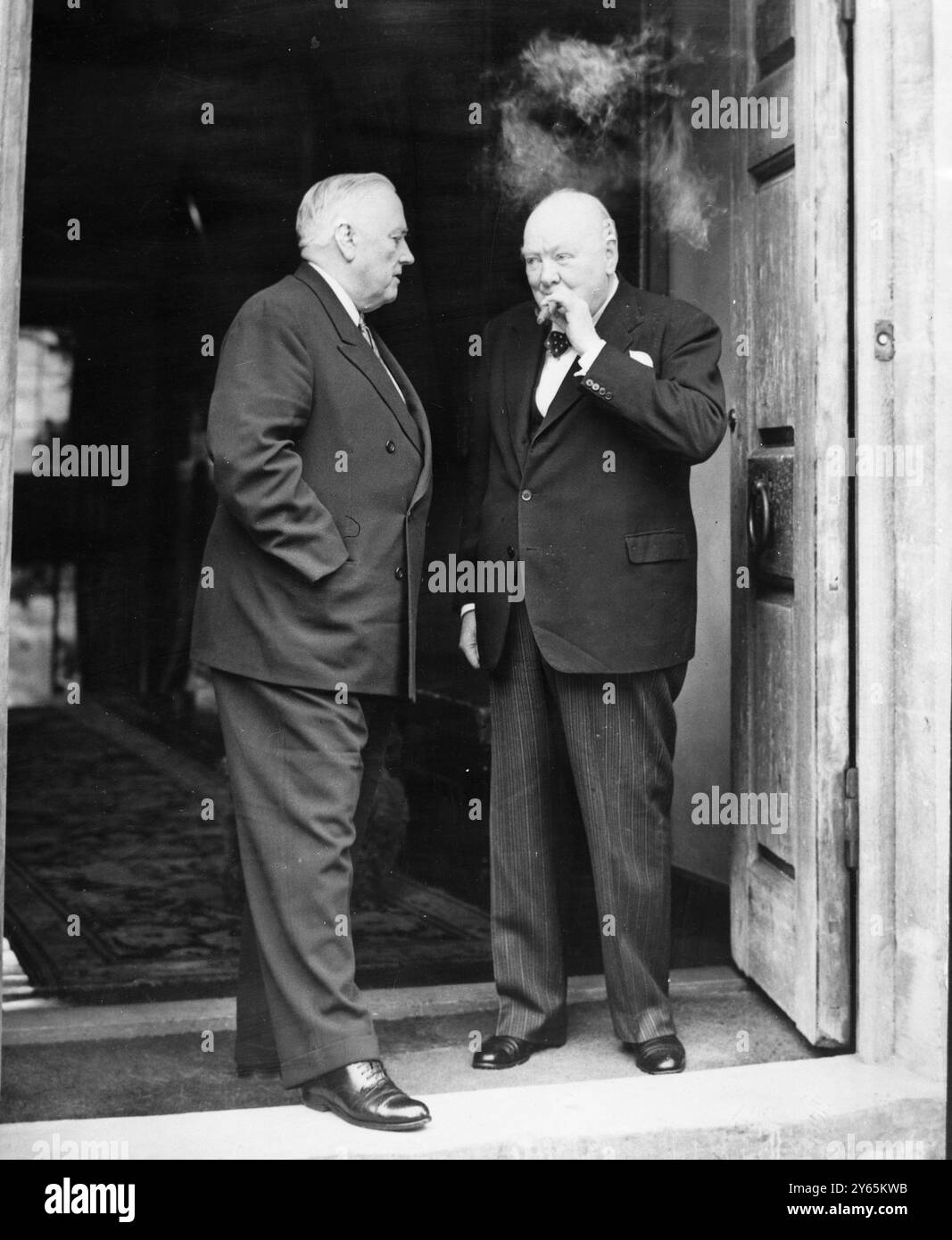 Parlez au milieu de la fumée de cigare . Le premier Ministre, Sir Winston Churchill, tire à son cigare alors qu'il s'entretient avec le sénateur Alexander Wiley , Président du Comité des relations étrangères du Sénat des États-Unis , après qu'ils eurent déjeuné ensemble à la maison de campagne de Sir Winston, ' Chartwell ' , Westerham , Kent . On pense qu'ils ont discuté de la situation après le rejet par la France du plan de Communauté européenne de défense. Le sénateur Wiley , qui s'est envolé pour la Grande-Bretagne depuis l'Allemagne , est en Europe ' pour faire certaines enquêtes ' 7 septembre 1954 Banque D'Images