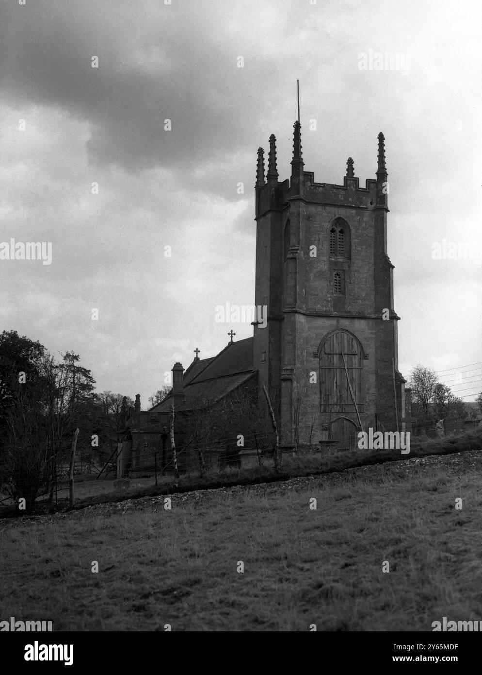 Les villageois d’Imber attendent depuis 1943 la permission de rentrer chez eux, mais ils savent maintenant que leur magnifique Domesday Village restera à jamais déserté au centre d’une école de combat militaire. La photo montre l'église du village à Imber avec ses grands vitraux remplacés par l'embarquement. La preuve d'une activité guerrière se trouve dans la tour, percée par un missile et dont l'une de ses créneaux a été détruite. 6 avril 1948 Banque D'Images