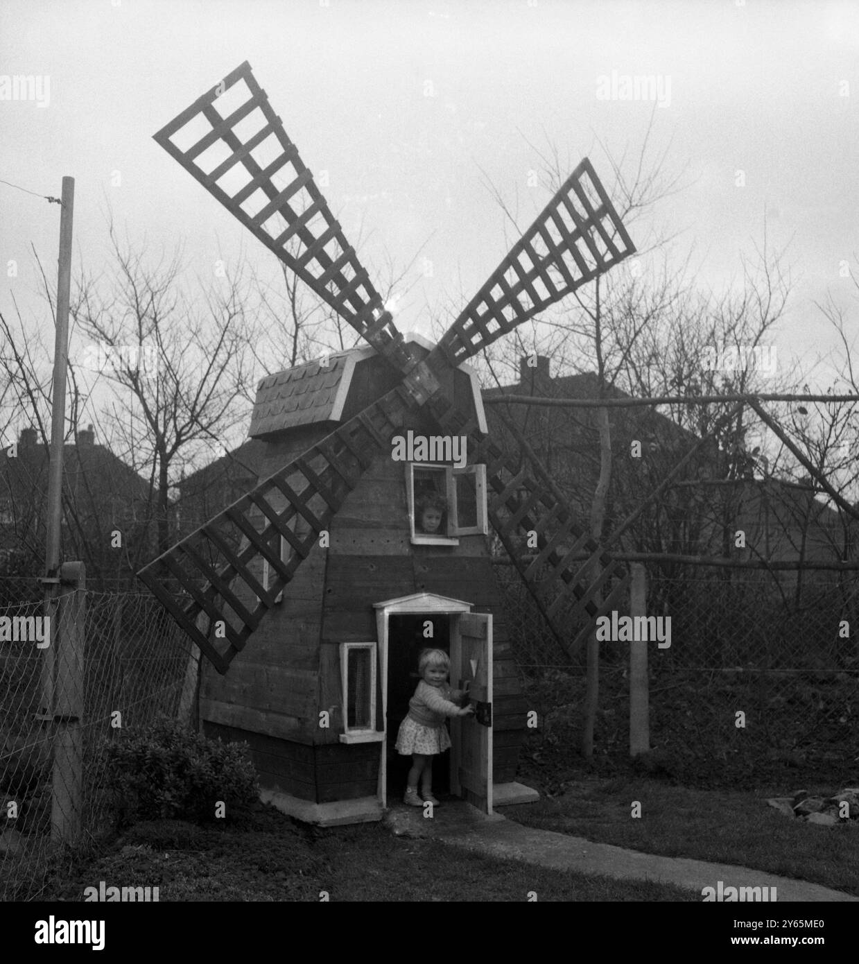 Denise Holmes, cinq ans, et sa sœur Nicola , deux ans, ont maintenant un moulin à vent au fond de leur jardin à Littlehampton , Sussex . Il a été fait comme une maison de jeu pour eux par leur père , charpentier Victor Holmes , qui a utilisé le bois d'une vieille clôture qu'il a fallu abattre . Les filles attendent maintenant que leur père fasse des meubles , mis à l'échelle pour correspondre au moulin de huit pieds de haut . 20 avril 1959 Banque D'Images