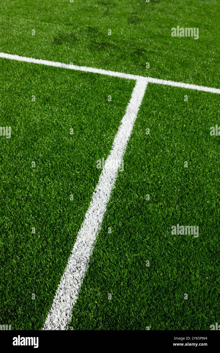 Cette image présente un gros plan de l'herbe verte synthétique et des lignes blanches nettes d'un terrain de football, mettant en évidence les motifs géométriques et la texture Banque D'Images