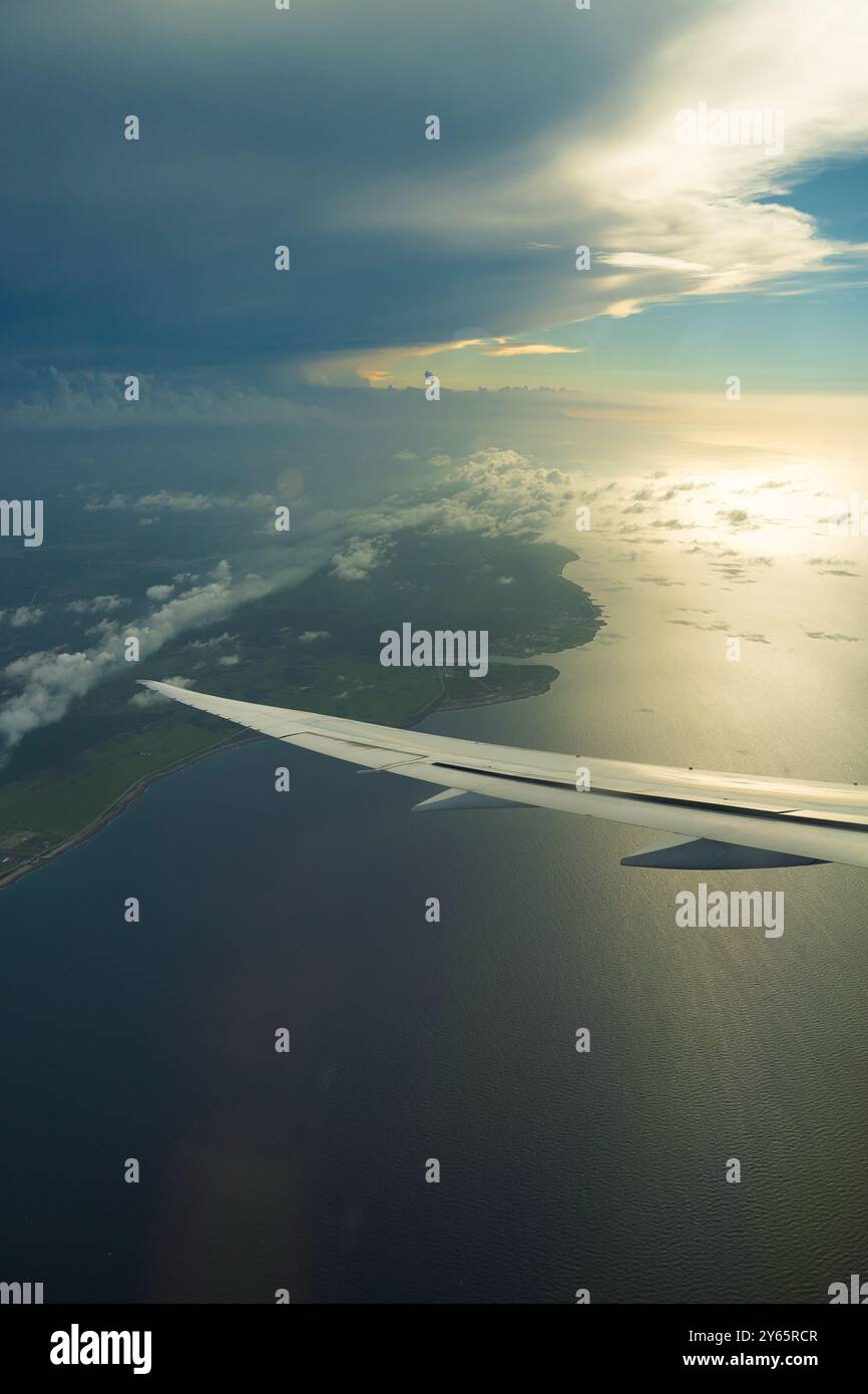 Photo aérienne captivante capturant le littoral et les formations nuageuses vues depuis le point de vue d'une aile d'avion lors d'un vol tranquille. Banque D'Images