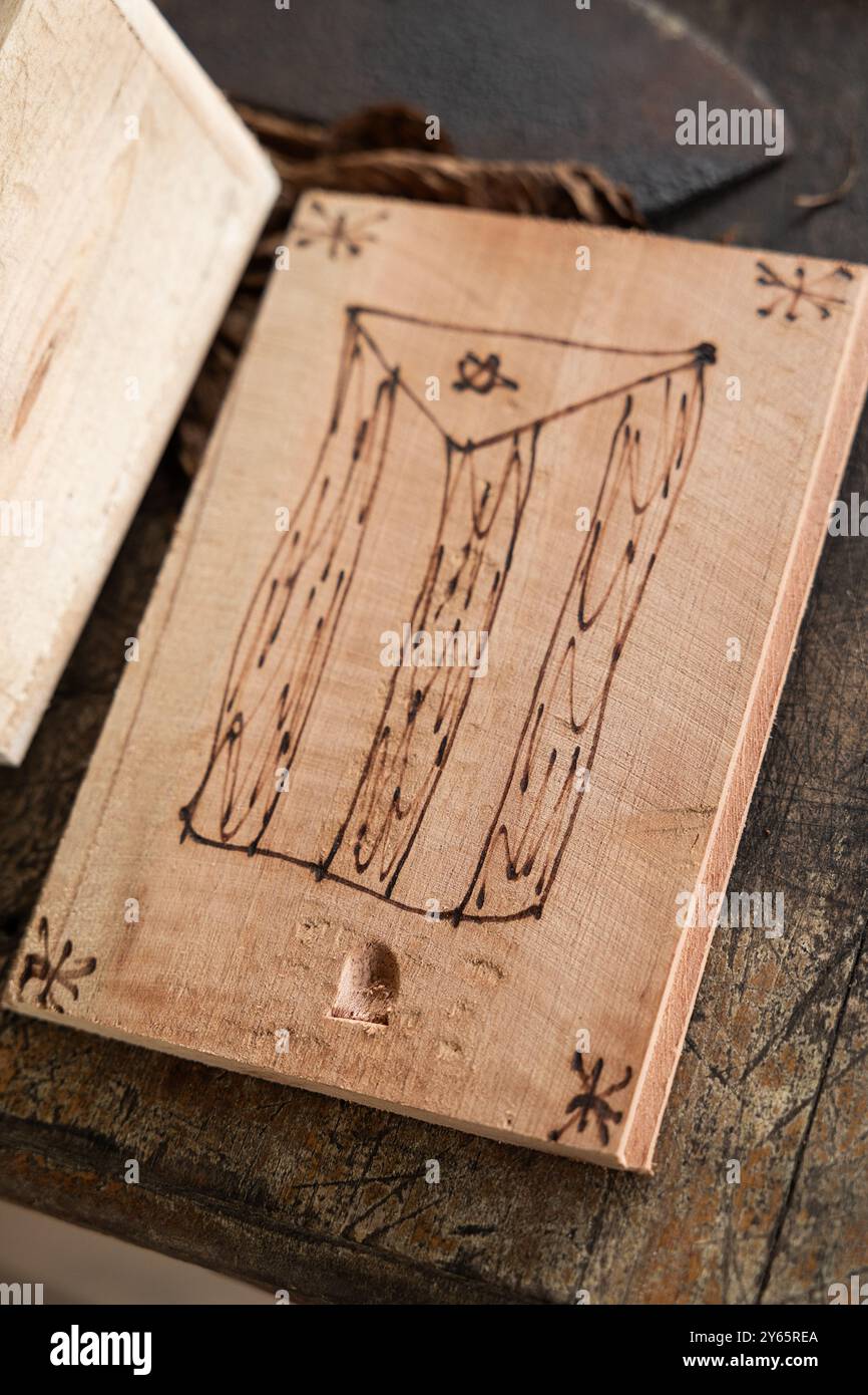 Gros plan d'une planche de bois avec un motif de drapeau cubain dessiné à la main, placé sur une surface rustique dans un atelier de fabrication de cigares L'image met en valeur les artisans Banque D'Images