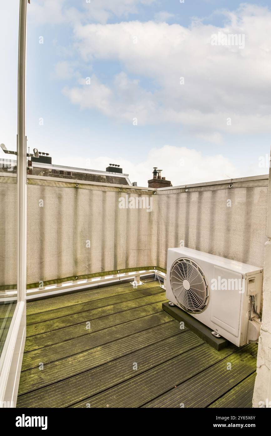 Un toit urbain en bois avec une unité de climatisation sur fond de ciel bleu et de nuages. Banque D'Images