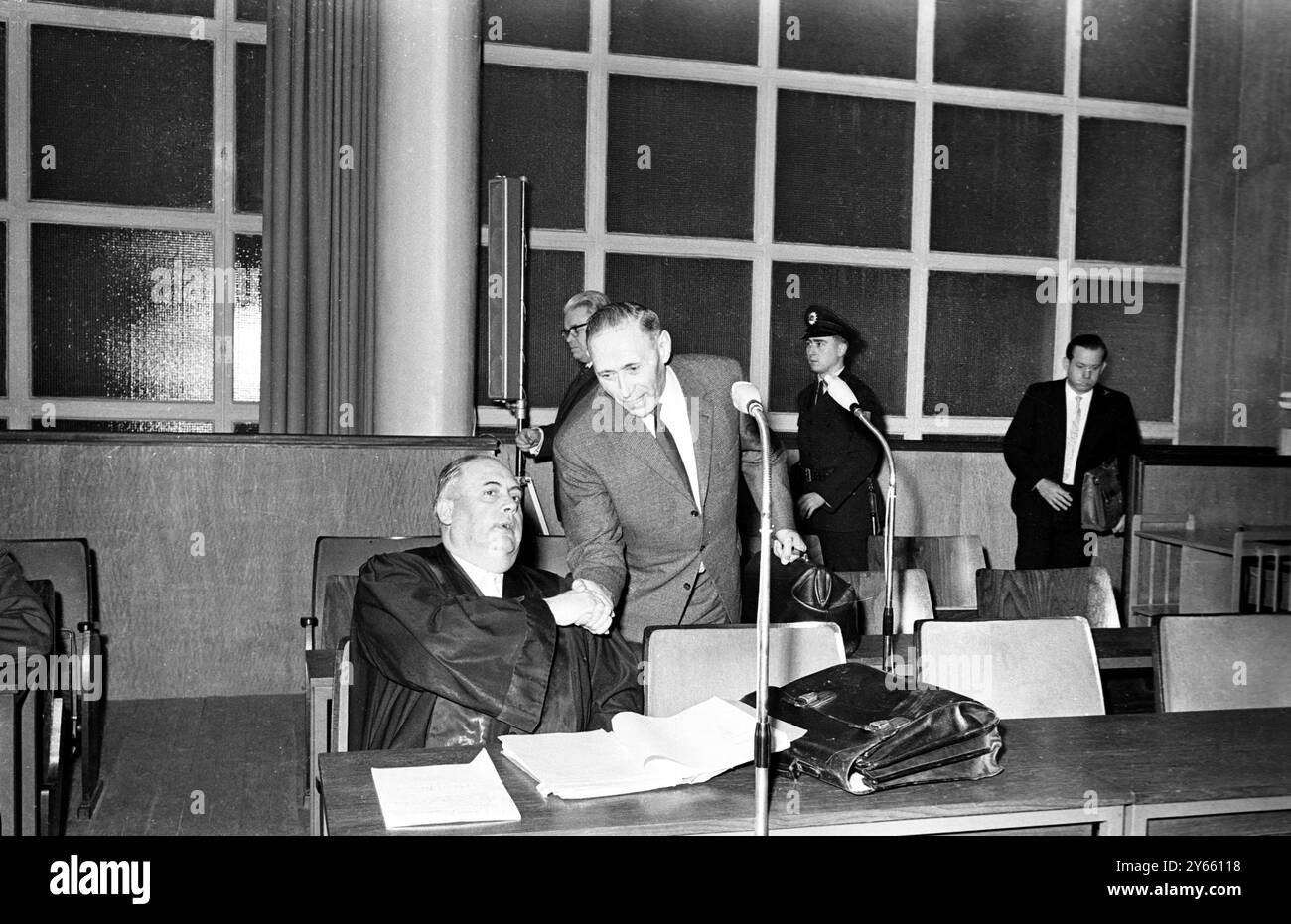 Concernant le procès pour crimes de guerre commis au camp de la mort d'Auschwitz , Wilhelm Boger (debout) salue son avocat de la défense, le Dr Rudolf Aschenauer, avant le début de la session du procès d'Auschwitz de Francfort , qui a repris après une inspection sur place de l'ancien camp de la mort par les juges et d'autres . Boger est l'un des 22 accusés accusés de l'extermination de 2,5 à 4 millions de personnes dans le camp de la mort. 21 décembre 1964 Banque D'Images