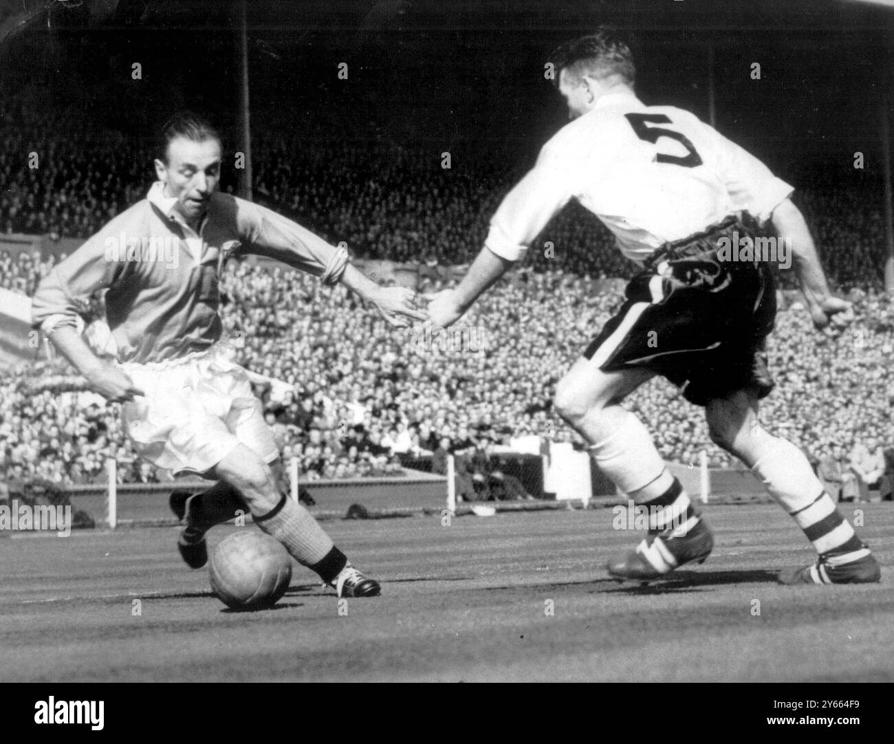 Finale de la FA Cup 1953 Bolton Wanderers contre Blackpool Stanley Matthews The Blackpool Outside Right, démontre son habileté sorcière alors qu'il dirige le ballon devant Bolton's Barrass lors de la finale de la FA Cup à Wembley. Matthews a mis ce ballon à Bill Perry qui a marqué le quatrième but et gagné. 2 mai 1953 Banque D'Images