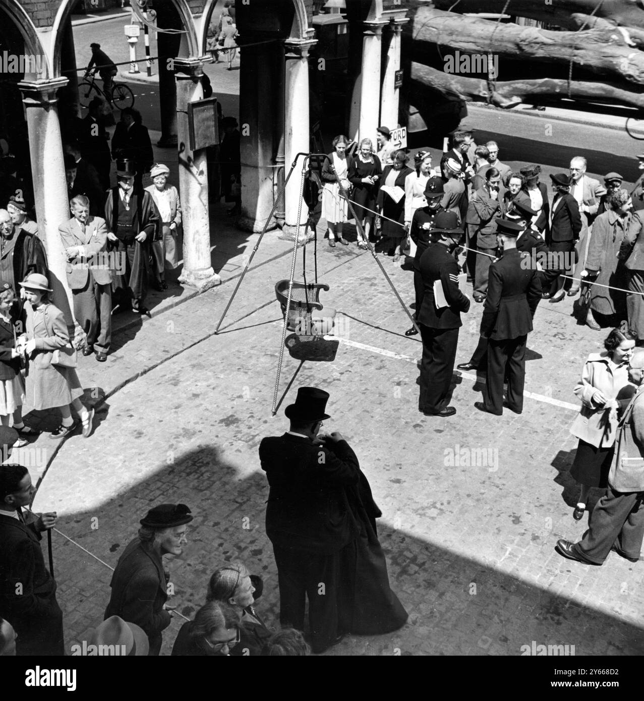 L'ancienne coutume de « peser dans » le maire et le conseil municipal de High Wycombe chaque année peut avoir son origine dans un contrôle de la quantité d'efforts que les conseillers ont mis dans leur travail. ARTICLE des années 1950 : « sur une place rodée de la place du marché de la petite ville de High Wycombe, Buckinghamshire, un trépied métallique a été érigé. De sa tête pend le cadran d'une balance à ressort, et de la balance bascule un fauteuil sans jambes. Quelques policiers se tiennent debout à bavarder sans rien faire dans l'enceinte. Les débuts d'une petite foule se rassemblent à l'extérieur des cordes, ou errent dans et hors du A. Banque D'Images