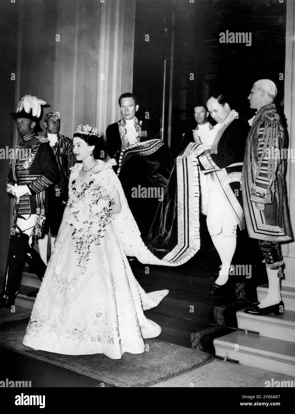 Le train de la Reine est soulevé par des hommes de pied alors qu'elle quitte Buckingham Palalce pour se rendre à l'abbaye de Westminster pour le couronnement. Sa robe est brodée avec l'emblème de la Grande-Bretagne et du Commonwealth. 2 juin 1953 Banque D'Images