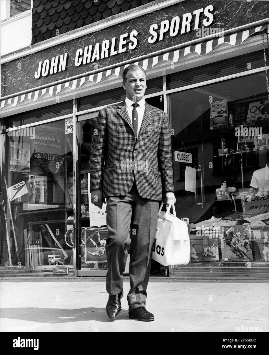 International gallois John Charles, qui était autrefois l'idole des fans de football italien. Le matin, il sert derrière le comptoir de son magasin de sport à Cardiff (en arrière-plan) et le client a toujours raison en ce qui concerne Big John. Puis il attrape le train ou les moteurs 50 miles au-dessus de la frontière galloise pour gérer l'équipe de la ligue du Sud, Hereford United. Maintenant âgé de 37 ans, Charles a l'intention de continuer à jouer au football hors ligue pendant une autre année. Pendant deux ans et demi avec Hereford Utd, il a marqué plus de 60 buts. 11 novembre 1968 Banque D'Images