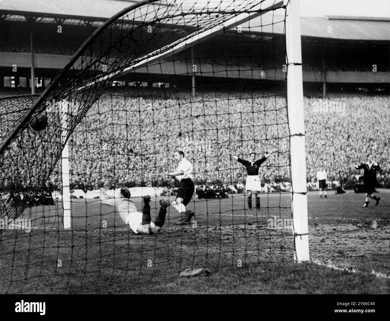 Écosse - Angleterre la balle est dans le filet, alors que le gardien de but écossais Cowan plonge en vain et Stanley Mortensen de Blackpool, l'attaquant central de l'Angleterre a marqué - mais il est hors-jeu - dans le match à Hampden Park à Glasgow. Un joueur écossais est attrayant et l'arbitre siffle. L'Angleterre a gagné le match 1-0, marqué par Roy Bentley de Chelsea. 16 avril 1950 Banque D'Images