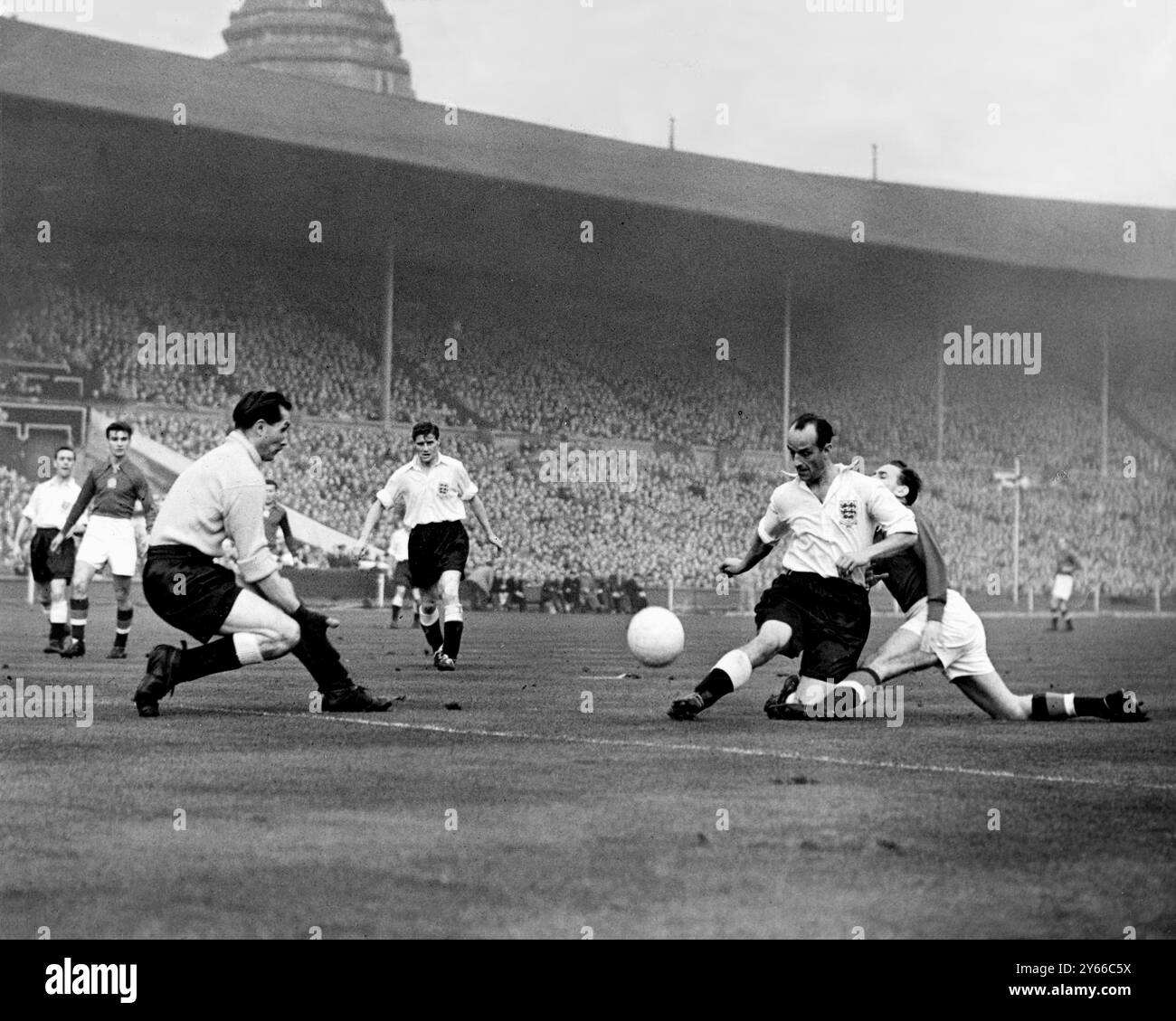 Angleterre v Hongrie Angleterre demi-centre H Johnston (chemise blanche) est défié par un attaquant hongrois - Gil Merrick, le gardien de but anglais (avant-plan gauche) attend de prendre le ballon lors de l'International à Wembley. L'Angleterre a perdu 6-3 - c'était leur première défaite contre un côté continental à la maison. 25 novembre 1953 Banque D'Images