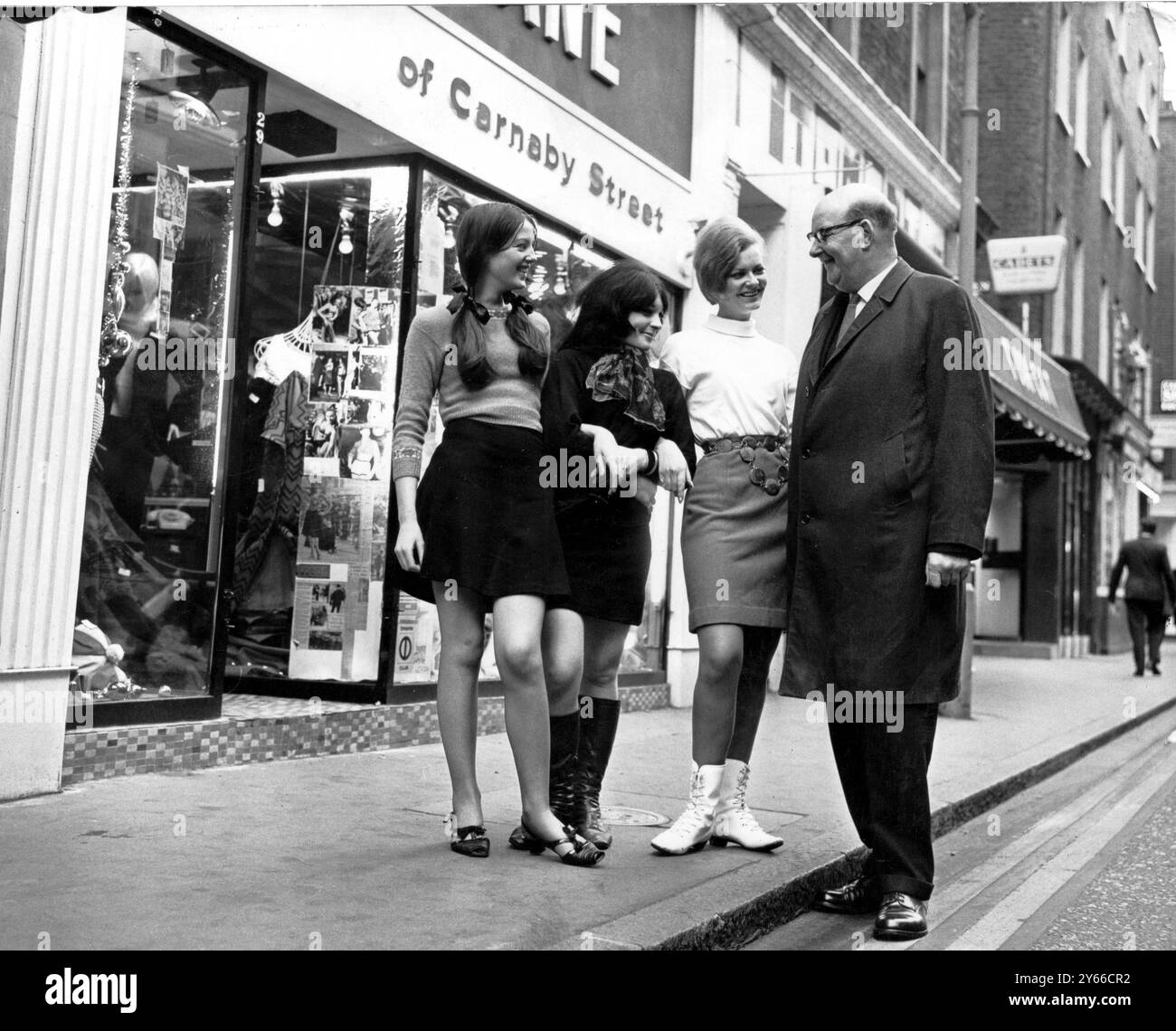 Piétons seulement à Londres Carnaby Street Sir William Fiske, chef du Greater London Council, a effectué une visite officieuse à Carnaby Street pour voir par lui-même si la rue pouvait être transformée en une zone sans circulation où les adolescents pouvaient faire leurs achats en toute sécurité. Il parle de son point de vue avec trois mini-filles à jupe qui travaillent à Carnaby Street Carola Parkinson, Vivienne Fisher et Jane Bradbury 19 décembre 1966 Banque D'Images