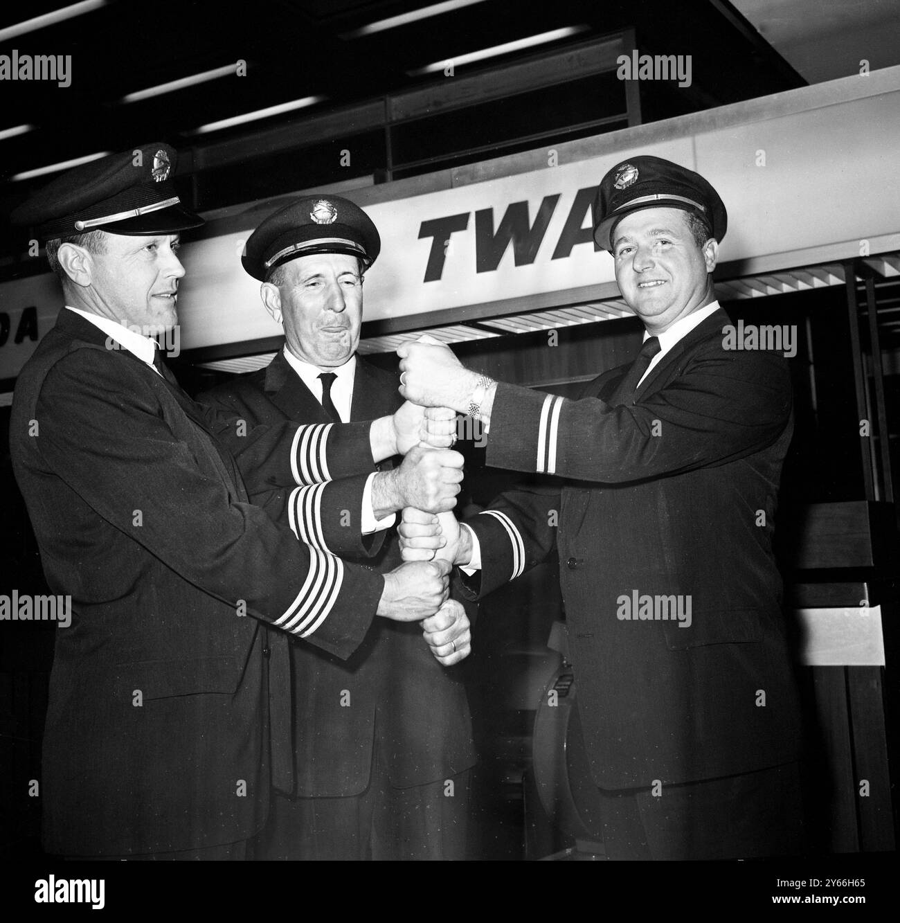 Presque Un record prenant le temps pour une petite célébration à l'aéroport de Londres hier soir, sont ces trois membres de l'équipage du vol 702 de TRANS World Airlines ( de gauche à droite ) premier officier Clifford Sparrow , capitaine D. W . Heath , et ingénieur Bob Hor . Les trois ont amené leur jet rugissant à Londres de New York en cinq heures 17 minutes, établissant presque un record pour le voyage. Ils ont été volés d'un record en étant retenus dans le schéma de vol pendant quatre minutes. Le jet a traversé l'Atlantique dans le jet stream avec 127 passagers et dix membres d'équipage à bord. À son arrivée , le capitaine Heath a commenté que c'était le cas Banque D'Images