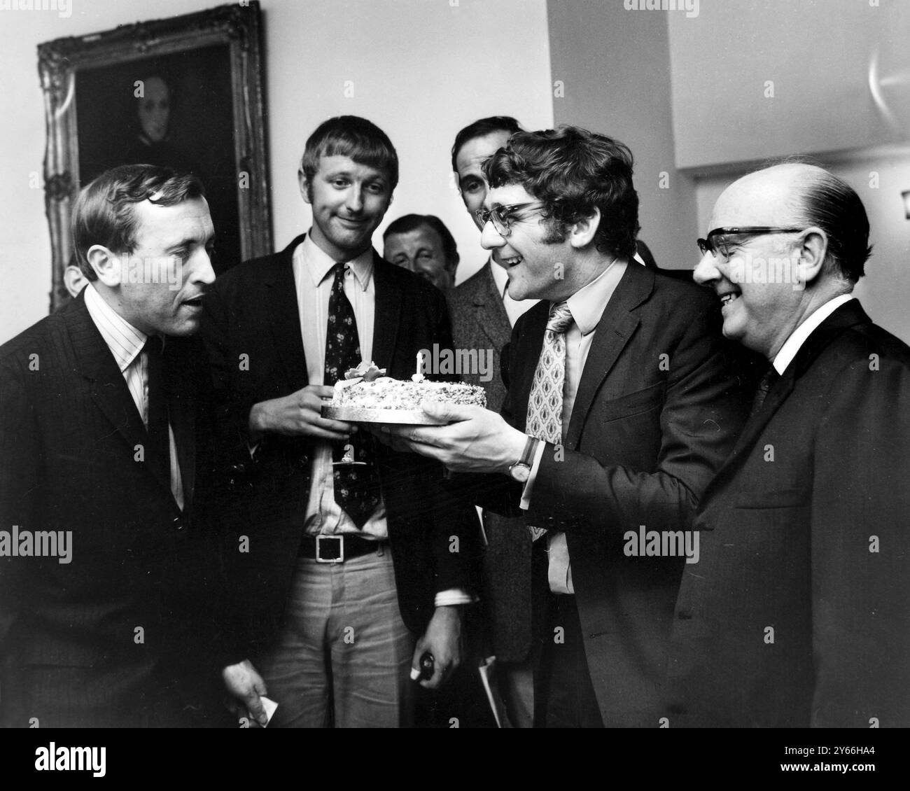 David Frost, personnalité de la télévision et intervieweur, jette un coup d'œil au gâteau d'anniversaire détenu par Kevin Billington qui réalisera le premier long métrage de M. Fros lors d'une réception organisée à Londres. La réception a eu lieu pour annoncer 'The Rise and Rise of Michael Rimmer' qui mettra en vedette John Cleese et Arthue Lowe. 12 juin 1969 Banque D'Images