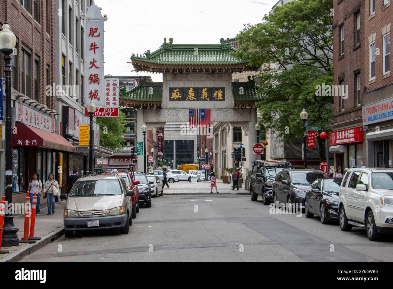 L'image montre une scène de rue animée dans un quartier Chinatown, dominé par une grande porte chinoise traditionnelle ou 'paifang' avec des toits de tuiles vertes Banque D'Images