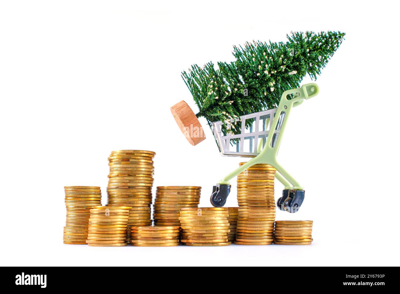 Chariot transportant un petit arbre de Noël au sommet de piles de pièces de monnaie, symbolisant les dépenses de vacances ou la planification financière festive. Banque D'Images