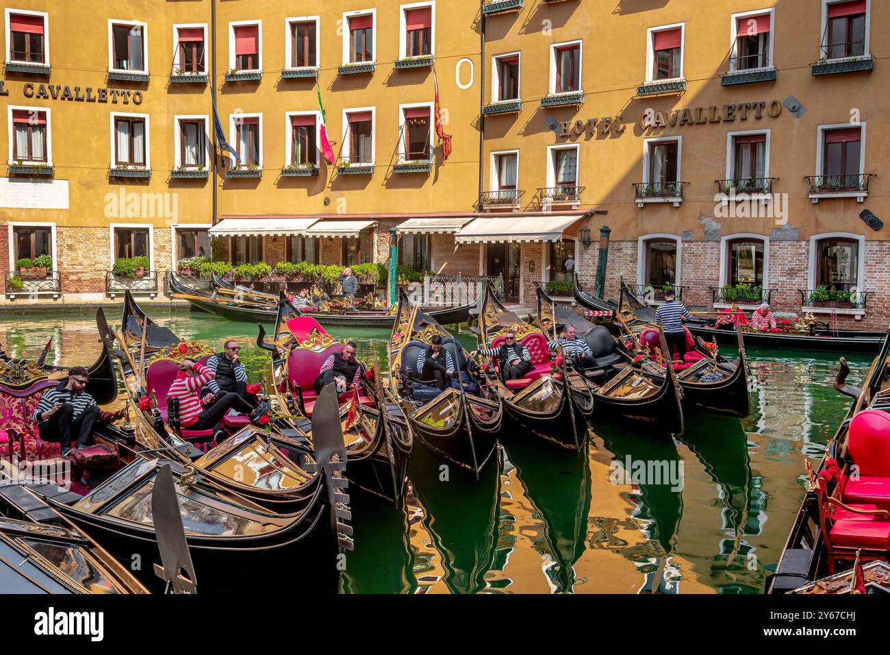 Gondoliers se relaxant dans leurs gondoles en profitant du soleil de printemps à Basino Oseolo dans le sestiere San Marco de Venise, Italie Banque D'Images