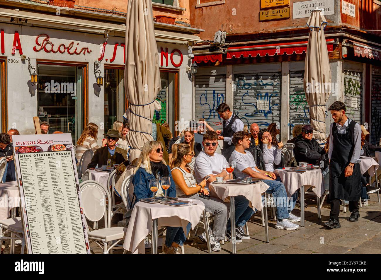 Les personnes assises dehors appréciant des boissons dans le soleil de printemps à Gelateria Paolin à Campo Santo Stefano dans le sestiere San Marco de Venise, Italie Banque D'Images