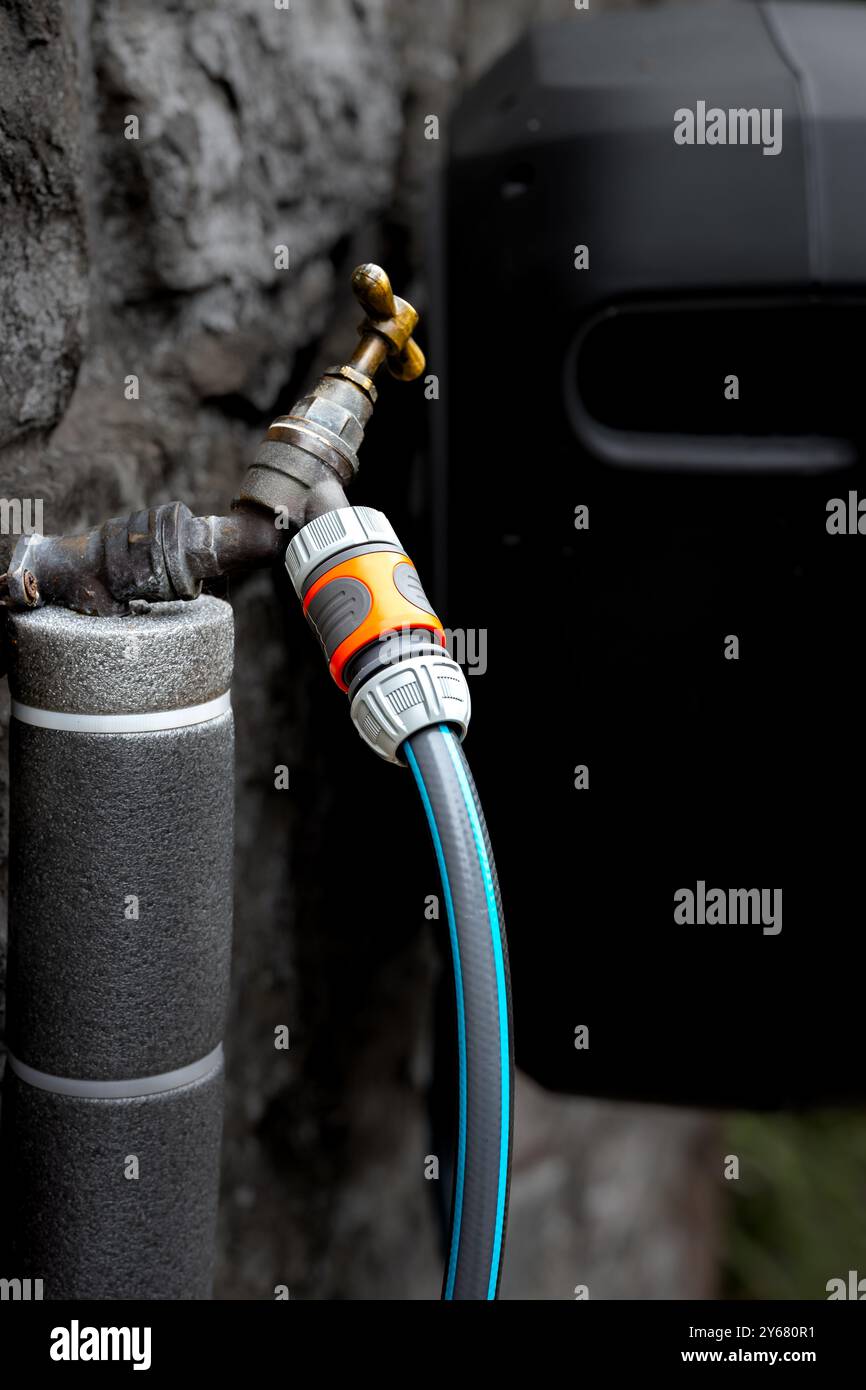 Tuyau d'eau isolé menant à un robinet d'eau externe en laiton à poignée en T de 1/2 pouce et à un tuyau d'arrosage. L'image est focalisée sur le point de connexion Banque D'Images