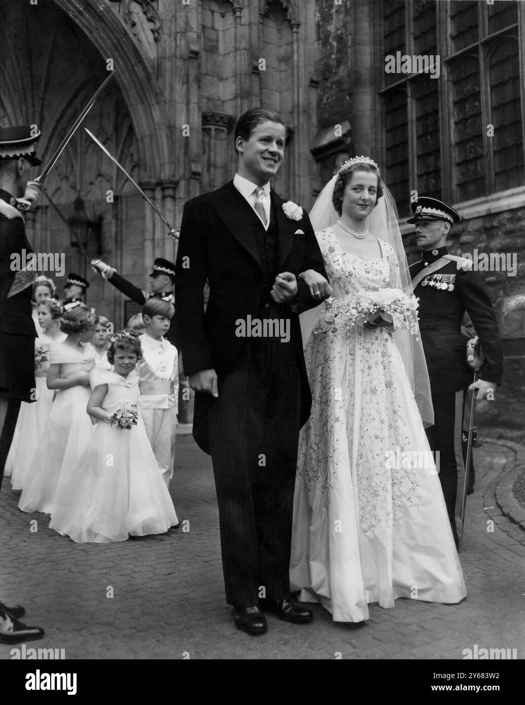 Peer's Daughter Weds in Abbey, Queen présente la belle mariée de 18 ans et son époux émergent de l'abbaye de Westminster après le «mariage de l'année». Avec la reine, le duc d'Édimbourg et d'autres membres de la famille royale comme invités, l'ancienne Miss Frances Roche, fille de Lord et Lady Fermoy, a été mariée à l'abbaye au vicomte Althorp, 30 ans, fils unique et héritier du comte et de la comtesse Spencer. La robe de la mariée est en faille blanche camélia brodée partout avec des paillettes argentées, des cristaux et des diamants taillés à la main. 1er juin 1954 Banque D'Images