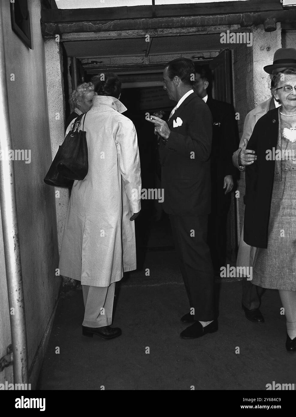 Ressemblant plus à un homme qu'à une femme, le personnage de gauche en blanc, n'est autre que l'actrice Katherine Hepburnavec des chaussures plates et un pantalon et une coiffure courte avec des sacs fourre-tout accrochés sur son épaule. Elle est arrivée à l'aéroport de Londres aujourd'hui de Montego Bay pour faire un film. Pour la rencontrer à l'aéroport était acteur-danseur de ballet Robert Helpman (à droite). Banque D'Images