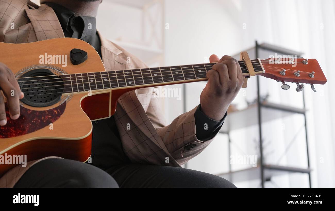 Pratique de la guitare. Jeu d'accords. Hobby musical. Homme talentueux artiste mains doigts exécutant la mélodie de chanson sur un instrument acoustique à l'intérieur à la maison. Banque D'Images