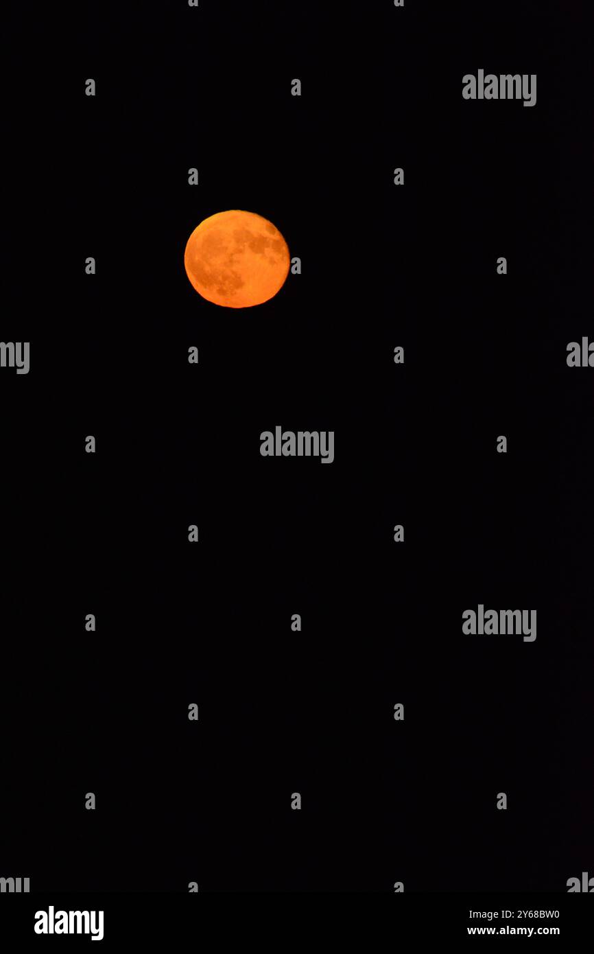 Une lune rouge envoûtante brille brillamment dans le ciel nocturne sombre, Banque D'Images