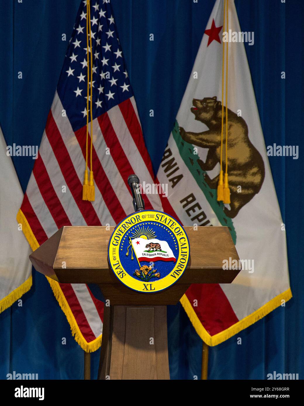 Sacramento, CA - 10 janvier 2024 : sceau du gouverneur de l'État de Californie sur un podium en bois avec les drapeaux américain et californien alternant derrière Banque D'Images