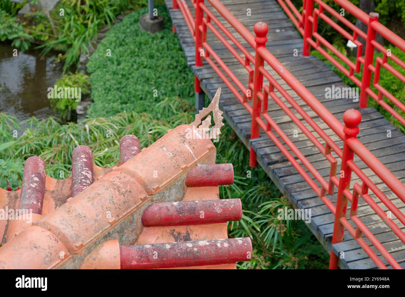 Pont rouge vif et détail de toit rustique dans les jardins luxuriants du palais monte Banque D'Images