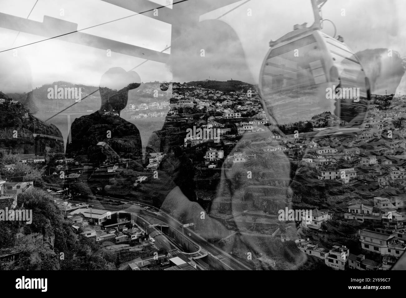 Reflets et ombres se fondent avec les maisons à flanc de colline dans une vue fascinante depuis le téléphérique tandis qu'un autre passe par là Banque D'Images