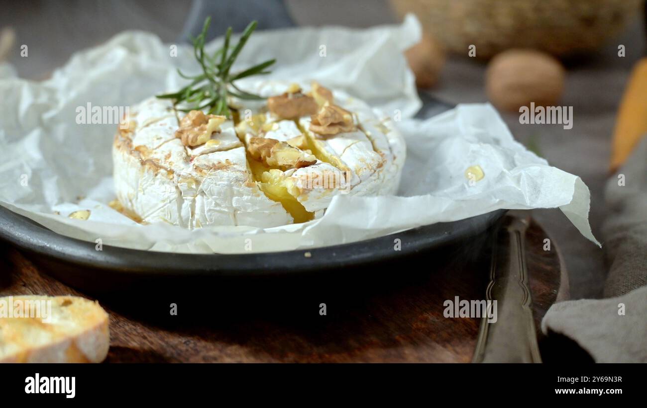 Type de fromage Brie. Camembert. Fromage Brie frais tranché sur un plateau en bois avec des noix, du miel et des feuilles. Italien, fromage français. Banque D'Images