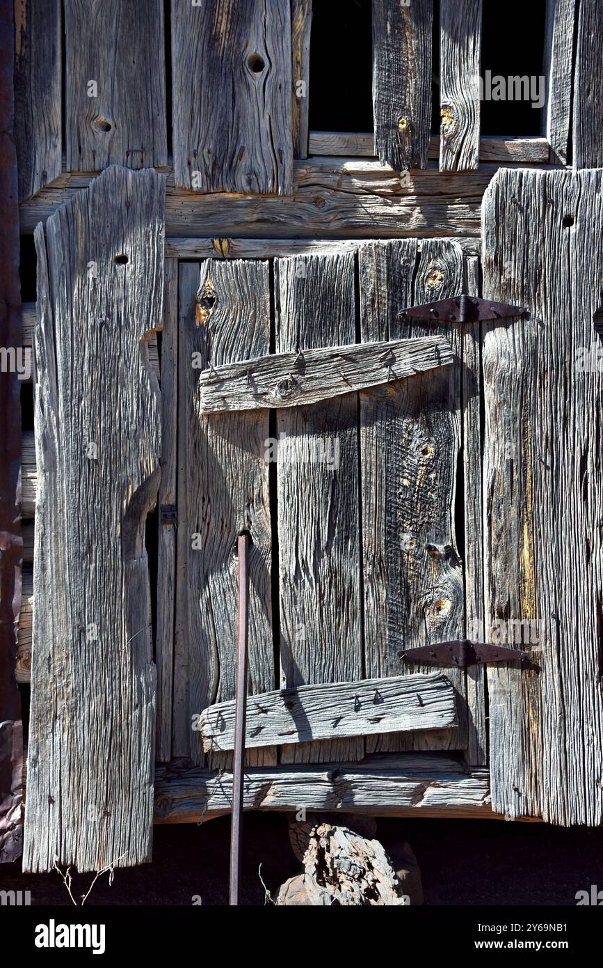 La porte d'entrée de la petite grange en rondins, au Nouveau-Mexique, est maintenue fermée avec une tige d'acier. Le bois est sec et fissuré, altéré et délavé. Banque D'Images