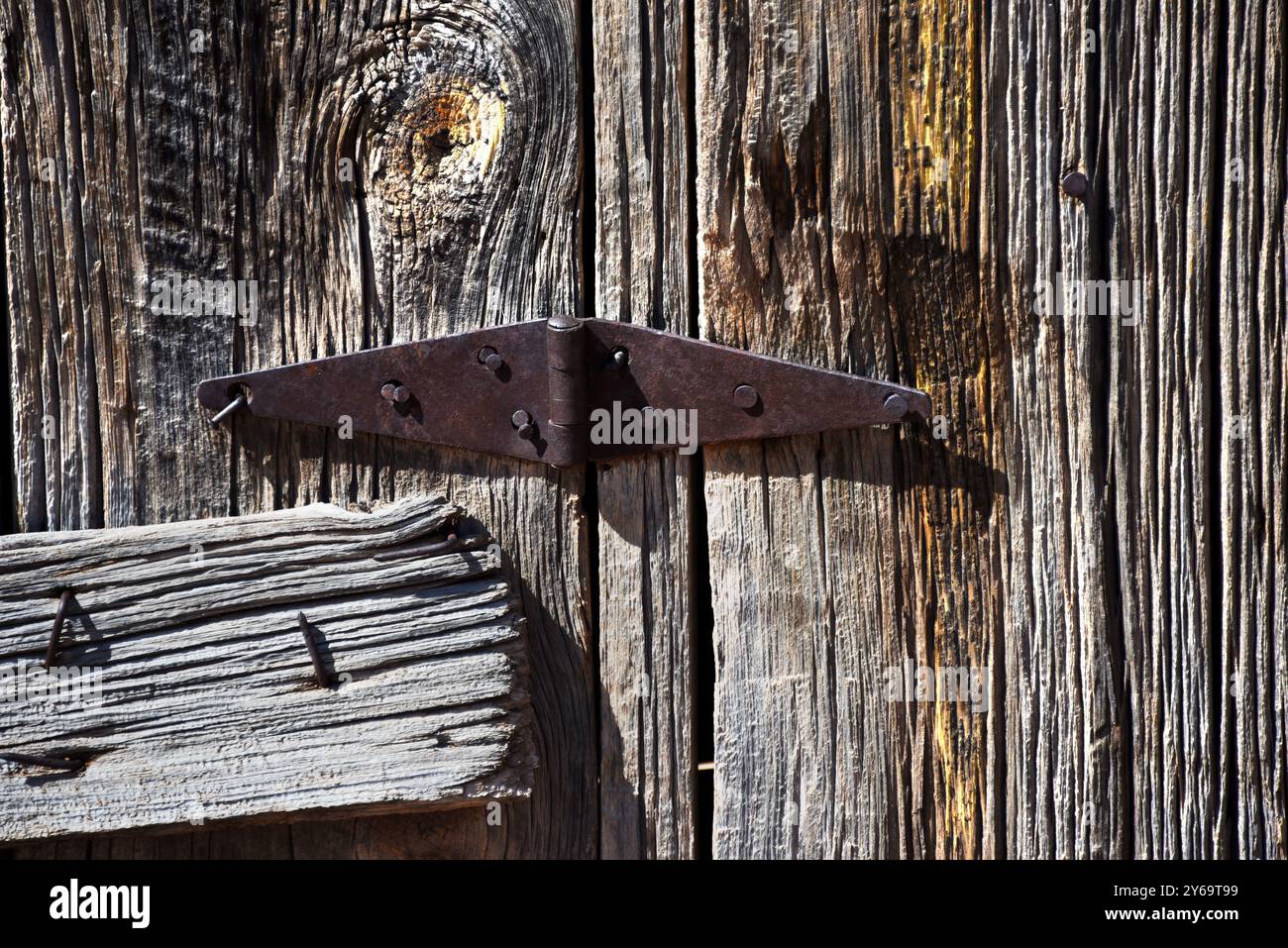 La charnière de porte rouillée, sur l'ancienne grange en rondins, a été clouée et louée à la structure. Certains clous sont pliés. Le bois est altéré et sec. Banque D'Images