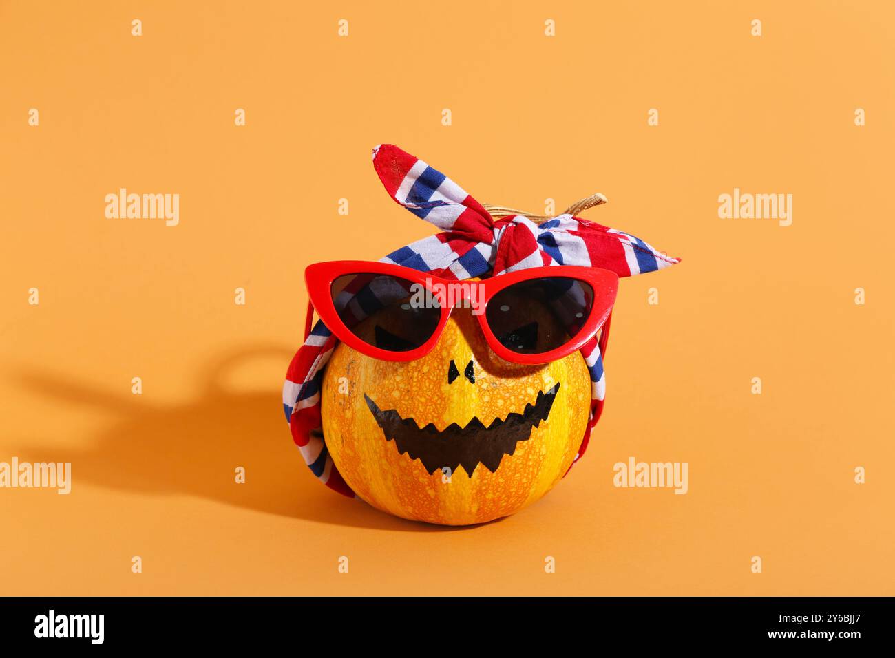 Citrouille d'Halloween dans des lunettes de soleil sur fond orange Banque D'Images