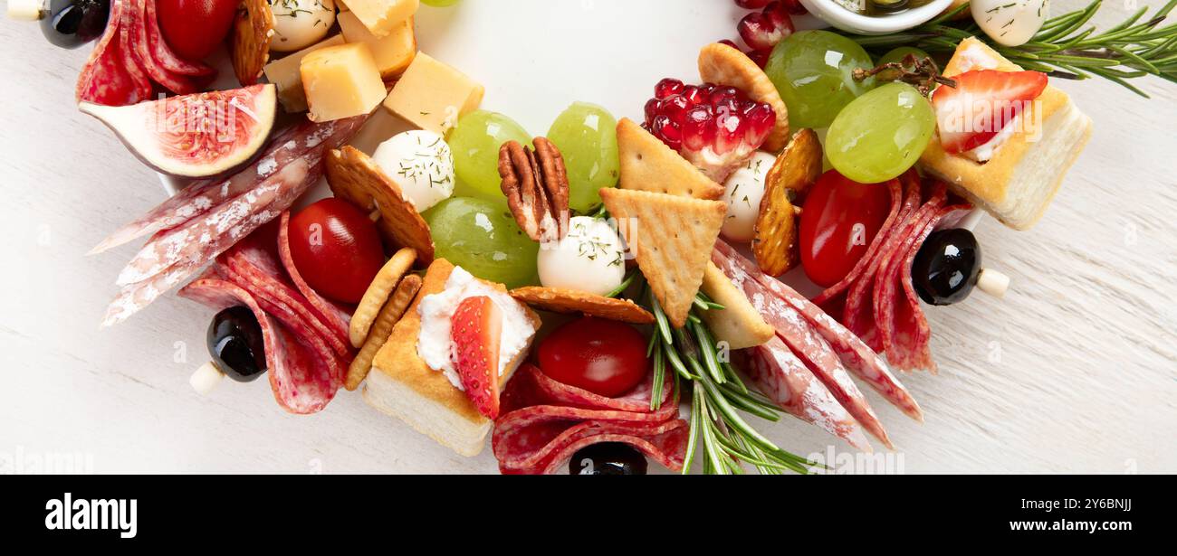 Couronne de Noël de collations festives. Canapés au fromage avec légumes et salami sur fond blanc. Couronne de nourriture de Noël. Vue de dessus. Panorama. Banque D'Images Couronne de Noël de collations festives. Canapés au fromage avec légumes et salami sur fond blanc. Couronne de nourriture de Noël. Vue de dessus. Panorama. Banque D'Images