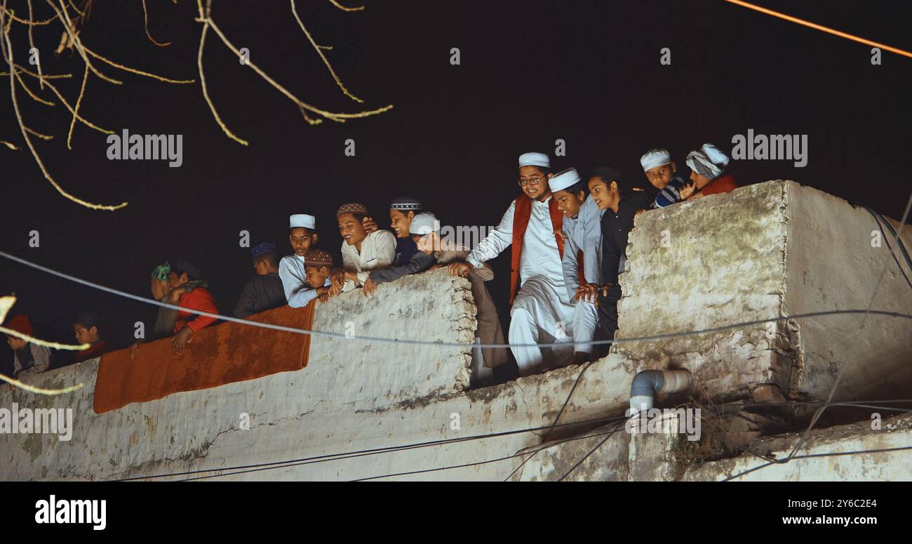 Agra, Uttar Pradesh, Inde. Les musulmans indiens regardent la cérémonie de mariage depuis le toit de la maison. Cortège indien de mariage hindou de Baraat. Procession du marié Banque D'Images