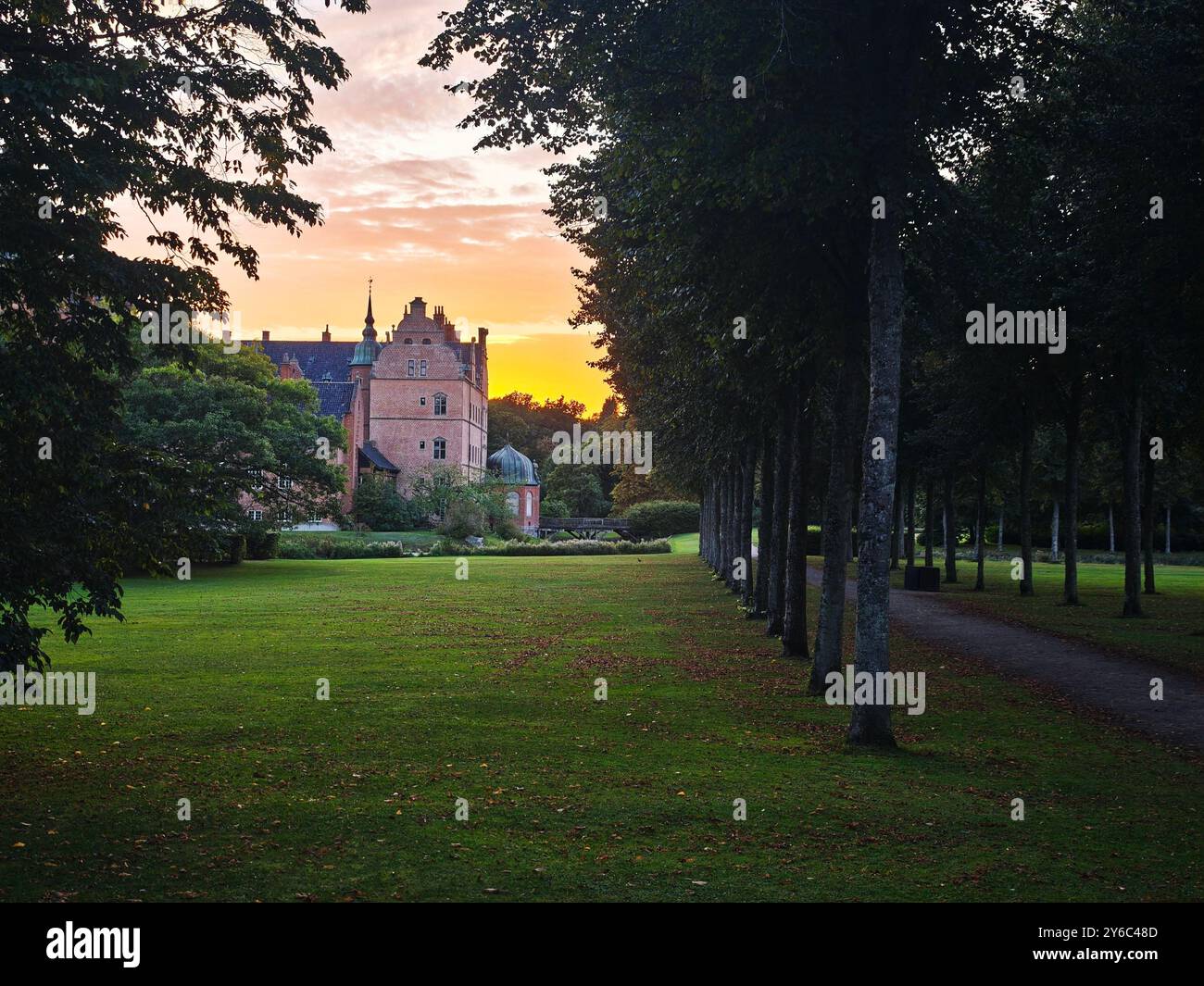 Une belle vue sur le coucher du soleil d'un vieux château entouré d'arbres verdoyants et d'une pelouse bien entretenue. Banque D'Images