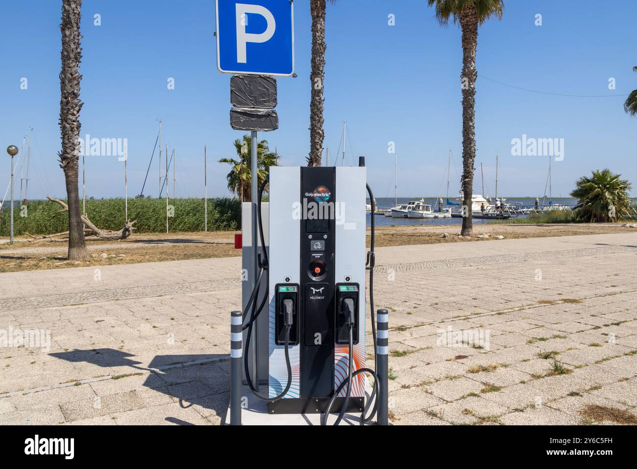 Station de recharge de véhicule électrique debout sur une zone pavée près d'une marina par une journée ensoleillée Banque D'Images