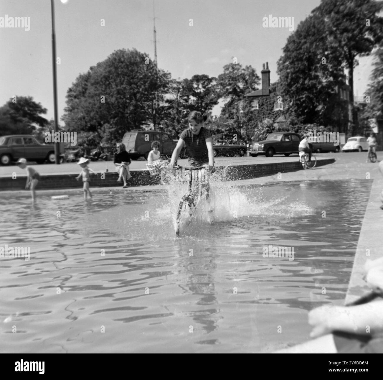 HAMPSTEAD - GABRIELLE TAYLOR RIDES VÉLO À TRAVERS UN ÉTANG DE PIERRE BLANCHE PENDANT LA VAGUE DE CHALEUR À LONDRES ; 2 JUIN 1963 Banque D'Images