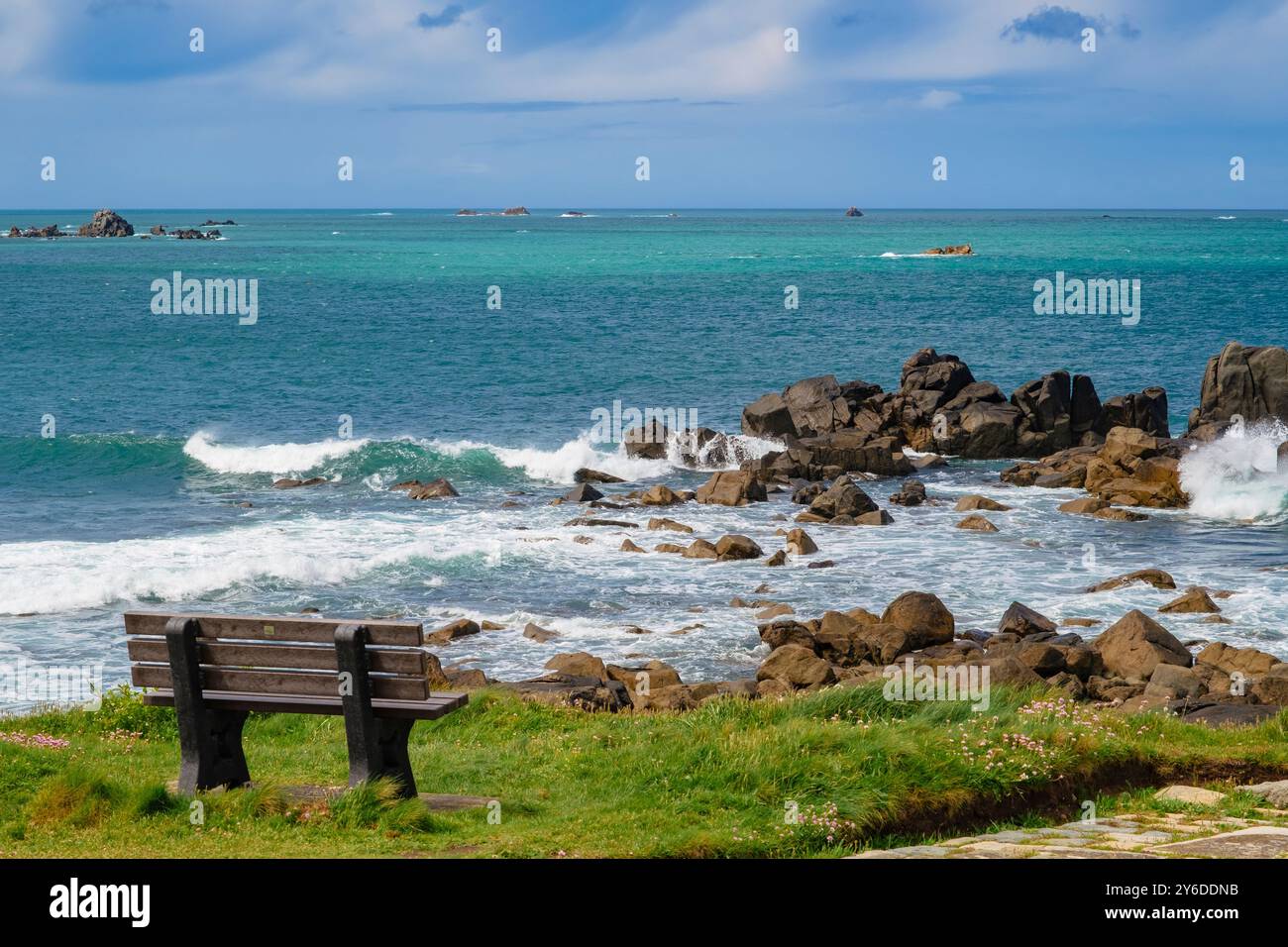 La baie de Grand Havre et un banc vide par le sentier côtier autour du promontoire de Chouet avec des vagues s'écrasant sur les rochers. Guernesey, Îles Anglo-Normandes, Royaume-Uni, Grande-Bretagne Banque D'Images