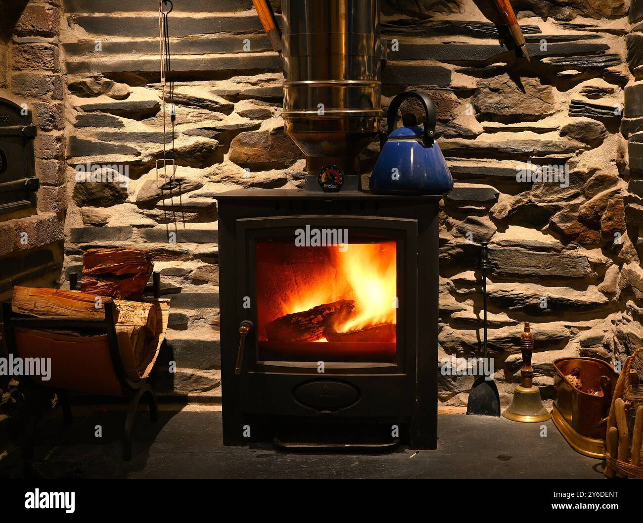 Poêle à bois, alight, situé en alcôve faite de blocs d'ardoise et quelques rochers. Banque D'Images