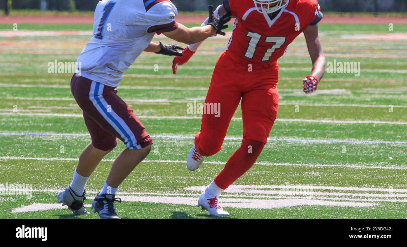Récepteur large Football High School passant devant le défenseur au début d'une partie pendant un match. Banque D'Images