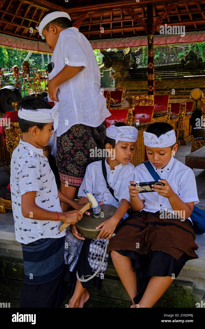 Indonésie, Bali, ville d'Ubud, temple Pura Samuan Tiga, enfants et téléphone portable Banque D'Images