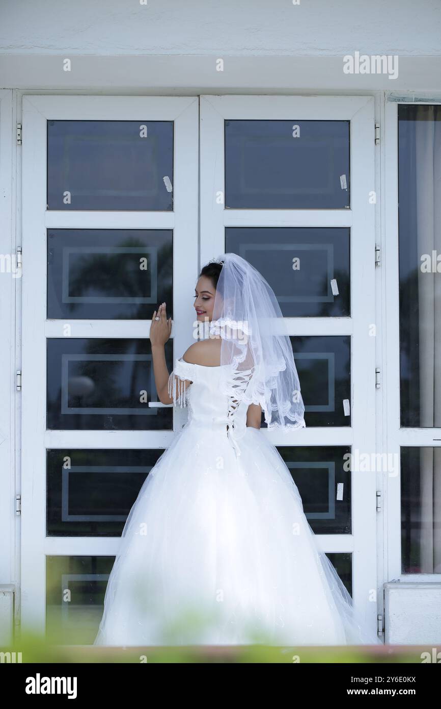 Belle fille blanche robe de mariée Reine bijoux fenêtre extérieure figure Glow Skin Garden Sit Stand Hotel Resort Lights Gardening Female Hostes Banque D'Images