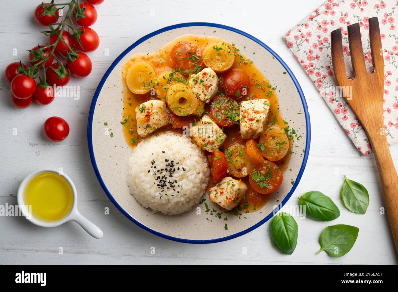 Ragoût de poisson blanc avec poireaux et tomates cerises servi avec du riz. Table vue sur le dessus avec décoration. Banque D'Images