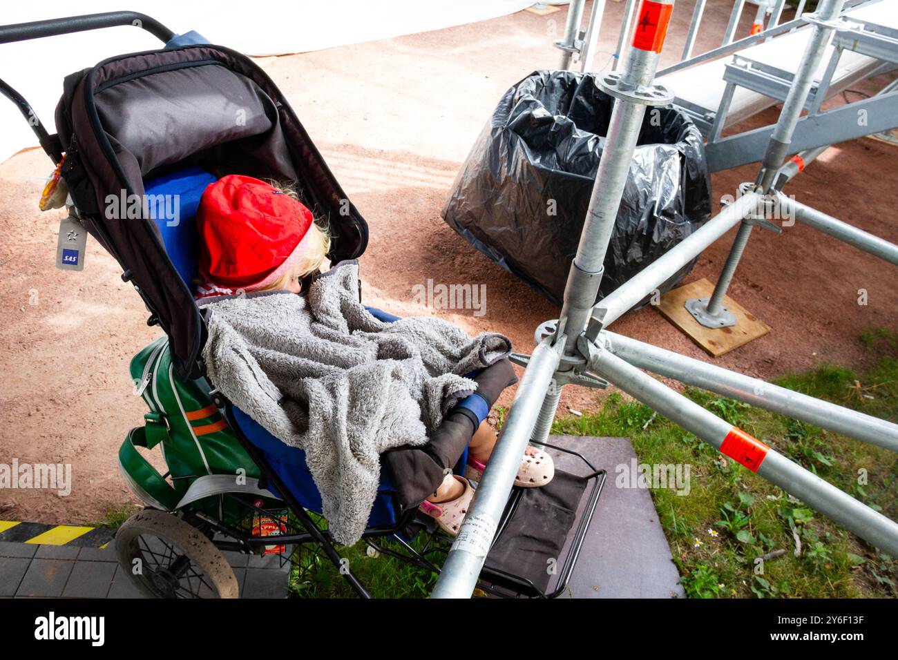 BÉBÉ DORT SOUS LES GRADINS DANS Une POUSSETTE, BEACH VOLLEY, MARIEHAMN, 2011 : bébé nordique typique dormant dans une poussette lors d'un événement public en août 2011 à l'Open PAF à Mariehamn, Åland, Finlande. Photographie : Rob Watkins. INFO : entre 2009-2013, le tournoi PAF Open Beach Volleyball était un événement annuel organisé à Mariehamn, Åland, Finlande. Il a attiré les meilleures équipes et joueurs internationaux dans le cadre du circuit mondial officiel de la FIVB, mettant en vedette le Beach volley de haut niveau. Banque D'Images