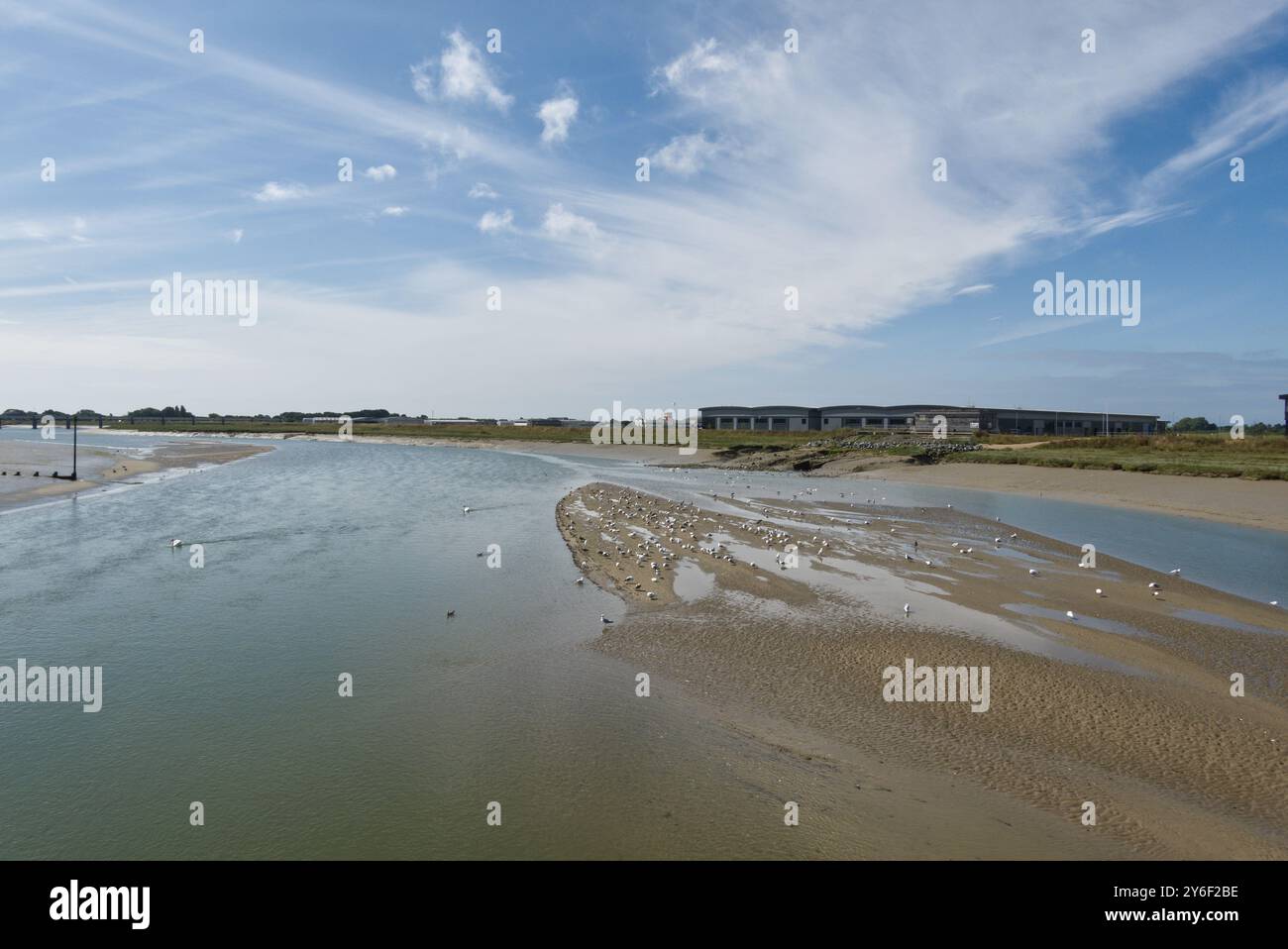 L'estuaire de la rivière Adur à Shoreham dans le Sussex de l'Ouest, Angleterre. Avec de nouveaux entrepôts sur le site de l'aéroport de Brighton City. Marée basse. Oiseaux sur les bancs de boue. Banque D'Images