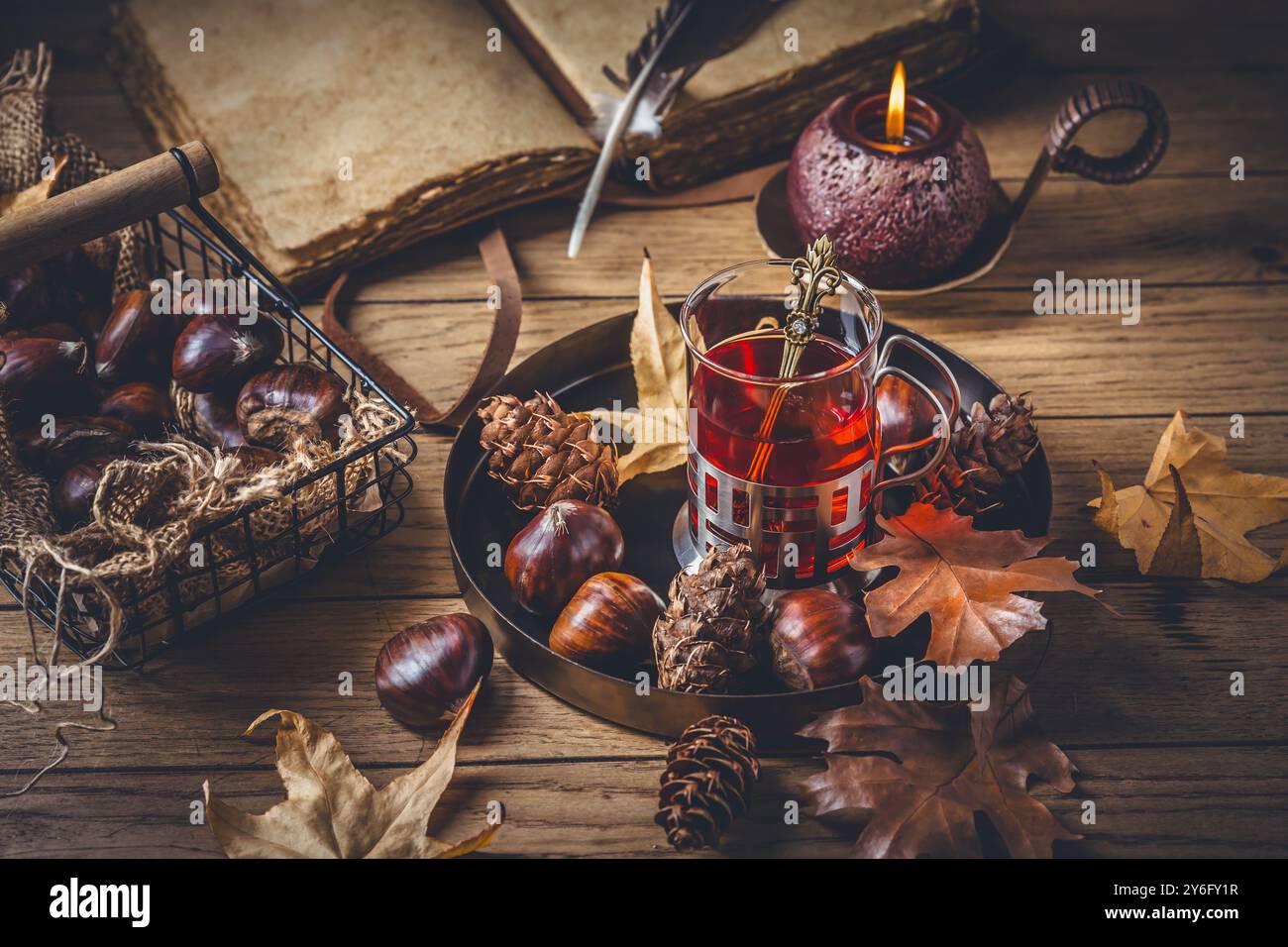 Thé aux fruits pour les journées froides d'automne, châtaignes avec des feuilles d'automne et vieux livre Banque D'Images