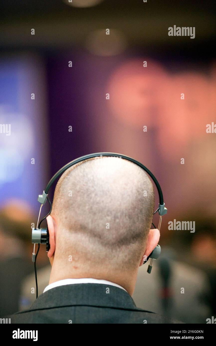 Un homme participe activement à une conférence à Dublin, utilisant des écouteurs pour les services de traduction. Banque D'Images