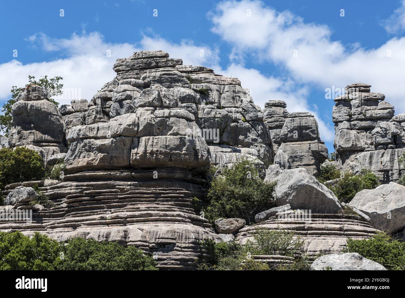 Formations rocheuses massives sous un ciel bleu avec nuages blancs et végétation verte, montagnes karstiques, Torcal Alto, El Torcal de Antequera, Sierra del Torc Banque D'Images